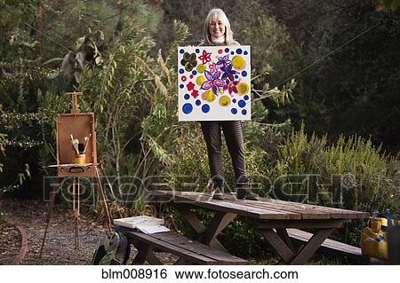 Caucasian woman holding painting outdoors View Large Photo Image Stock Photograph - Caucasian woman holding painting outdoors. Fotosearch