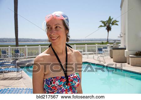 Stock Photo - Caucasian woman in goggles and swim cap by swimming pool. Fotosearch
