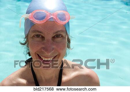 Caucasian woman in goggles and swim cap by swimming pool View Large Photo Image Stock Photo - Caucasian woman in goggles and swim cap by swimming pool. Fotosearch