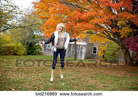 Stock Photo - Caucasian woman jumping for joy in backyard. Fotosearch