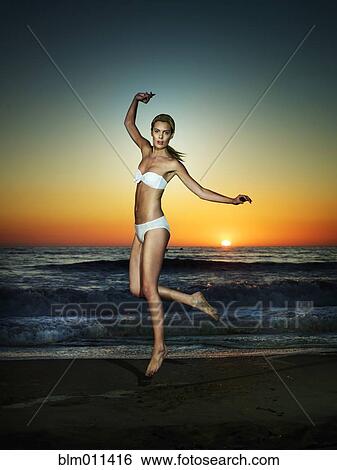 Stock Photograph - Caucasian woman jumping on beach. Fotosearch