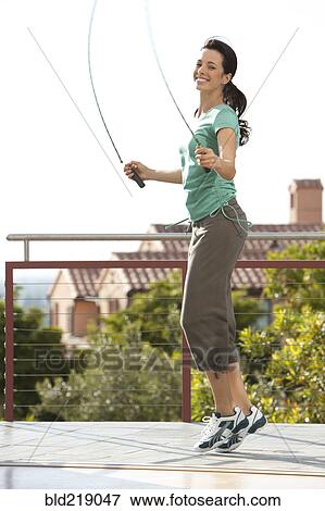 Stock Photo - Caucasian woman jumping rope on urban rooftop. Fotosearch