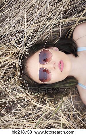Stock Photo - Caucasian woman laying in hay. Fotosearch