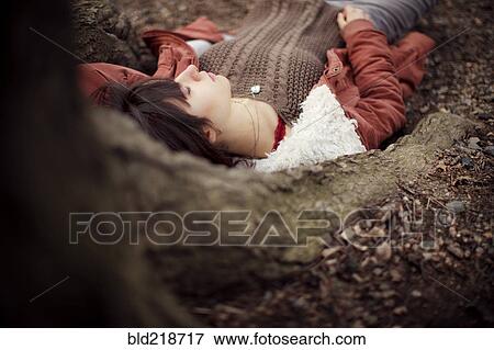 Stock Photo - Caucasian woman laying under tree. Fotosearch