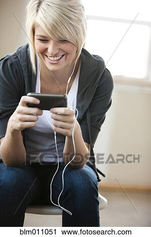 Stock Image - Caucasian woman listening to music on mp3 player. Fotosearch