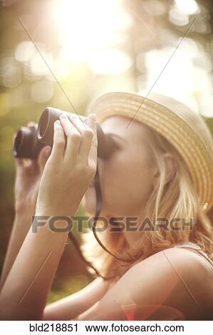 Stock Image - Caucasian woman looking through binoculars. Fotosearch