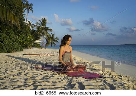 Stock Photography - Caucasian woman meditating on tropical beach. Fotosearch
