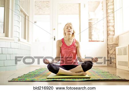 Stock Image - Caucasian woman meditating on yoga mat. Fotosearch
