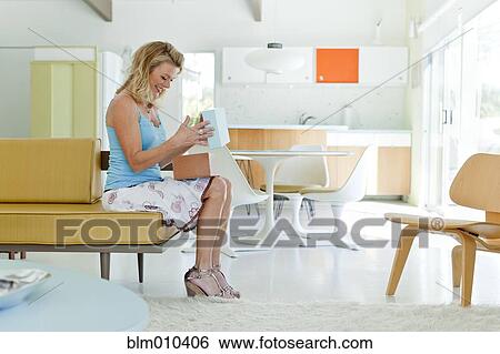 Stock Photograph - Caucasian woman opening box in living room. Fotosearch