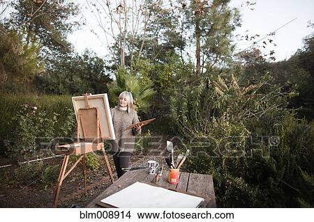 Caucasian woman painting on easel outdoors View Large Photo Image Picture - Caucasian woman painting on easel outdoors. Fotosearch