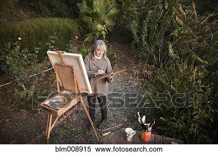 Caucasian woman painting on easel outdoors View Large Photo Image Stock Photography - Caucasian woman painting on easel outdoors. Fotosearch