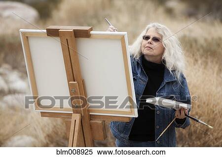 Caucasian woman painting on easel outdoors View Large Photo Image Stock Photography - Caucasian woman painting on easel outdoors. Fotosearch