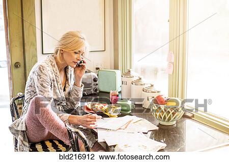 Caucasian woman paying bills on telephone in kitchen View Large Photo Image Stock Image - Caucasian woman paying bills on telephone in kitchen. Fotosearch
