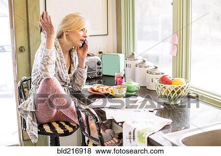 Caucasian woman paying bills on telephone in kitchen View Large Photo Image Stock Photo - Caucasian woman paying bills on telephone in kitchen. Fotosearch