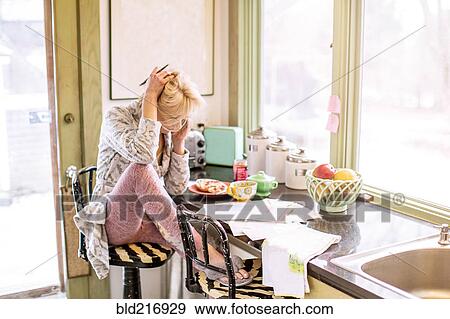 Caucasian woman paying bills on telephone in kitchen View Large Photo Image Stock Photo - Caucasian woman paying bills on telephone in kitchen. Fotosearch