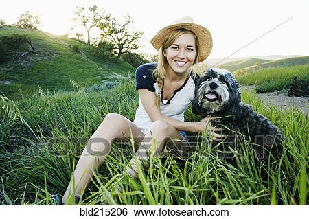 Stock Photograph - Caucasian woman petting dog in field. Fotosearch
