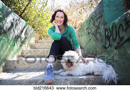 Caucasian woman petting dog on staircase with graffiti View Large Photo Image Stock Image - Caucasian woman petting dog on staircase with graffiti. Fotosearch