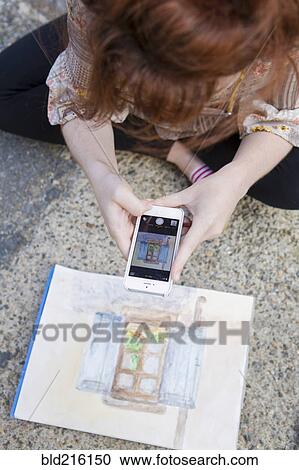 Caucasian woman photographing painting on ground View Large Photo Image Stock Image - Caucasian woman photographing painting on ground. Fotosearch