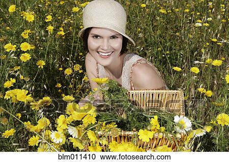 Stock Image - Caucasian woman picking wildflowers in field. Fotosearch