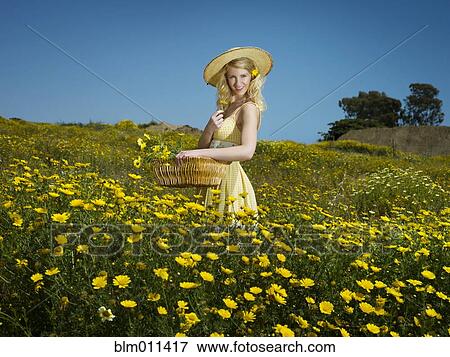 Stock Photo - Caucasian woman picking wildflowers in field. Fotosearch
