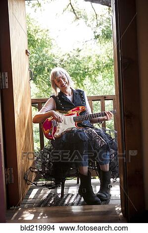Picture - Caucasian woman playing electric guitar on porch. Fotosearch