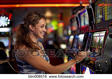 Stock Photograph - Caucasian woman playing slot machine in casino. Fotosearch