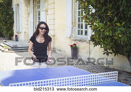 Stock Image - Caucasian woman playing table tennis in yard. Fotosearch