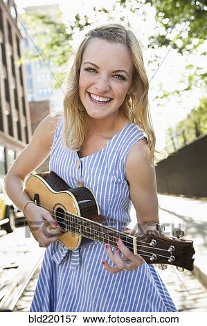 Caucasian woman playing ukulele in city View Large Photo Image Stock Photo - Caucasian woman playing ukulele in city. Fotosearch