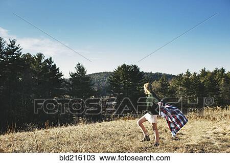 Stock Image - Caucasian woman playing with scarf on rural hilltop. Fotosearch