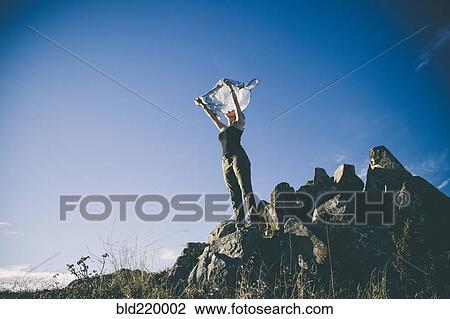 Stock Image - Caucasian woman playing with scarf on remote hilltop. Fotosearch