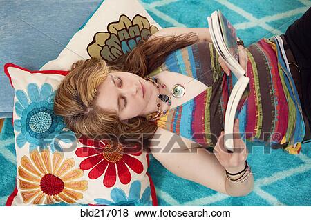 Stock Photo - Caucasian woman reading book on floor. Fotosearch