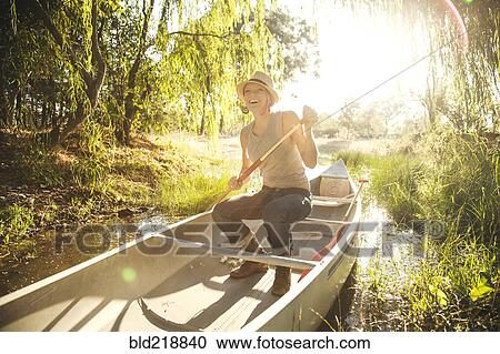Stock Image - Caucasian woman rowing canoe in rural creek. Fotosearch