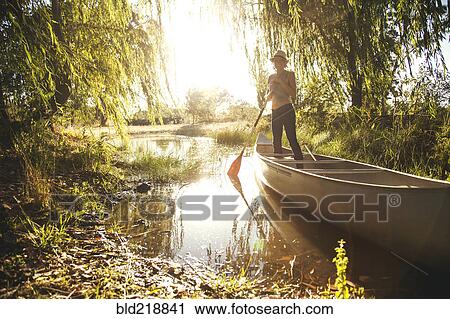 Stock Image - Caucasian woman rowing canoe in rural creek. Fotosearch