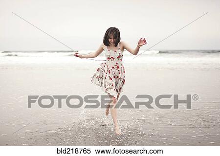 Stock Photography - Caucasian woman running in waves on beach. Fotosearch