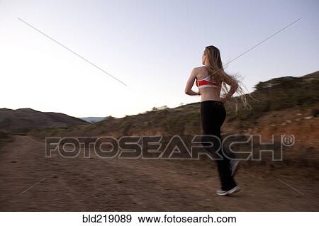 Stock Photo - Caucasian woman running on dirt path. Fotosearch