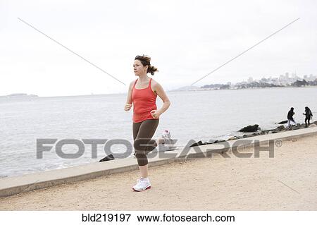 Stock Photo - Caucasian woman running on waterfront. Fotosearch