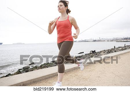 Stock Photo - Caucasian woman running on waterfront. Fotosearch