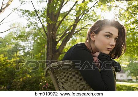 Stock Image - Caucasian woman sitting in chair outdoors. Fotosearch