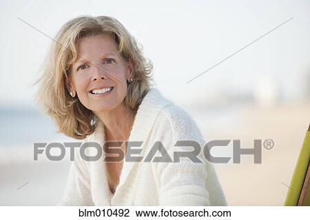 Stock Image - Caucasian woman sitting on beach. Fotosearch