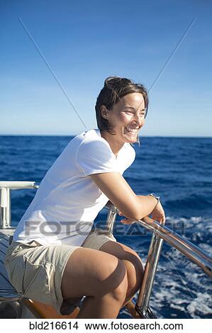 Picture - Caucasian woman sitting on boat deck. Fotosearch