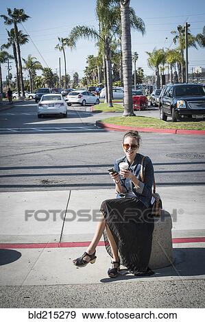 Caucasian woman sitting on concrete barrier in parking lot View Large Photo Image Stock Photo - Caucasian woman sitting on concrete barrier in parking lot. Fotosearch