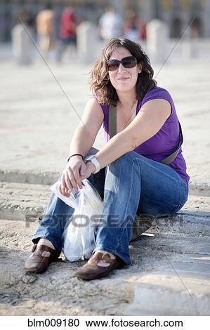 Stock Image - Caucasian woman sitting on steps. Fotosearch