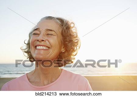 Stock Image - Caucasian woman smiling at beach. Fotosearch