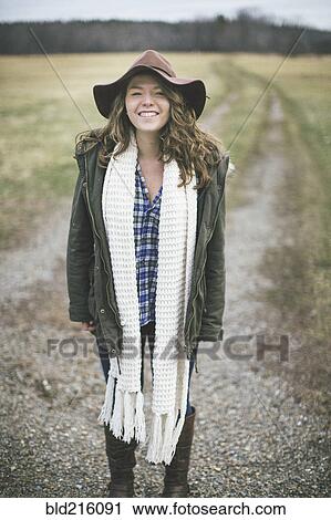 Stock Image - Caucasian woman smiling on dirt path in rural field. Fotosearch