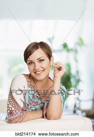 Picture - Caucasian woman smiling on sofa. Fotosearch