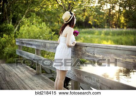 Caucasian woman standing on bridge over rural pond View Large Photo Image Stock Photography - Caucasian woman standing on bridge over rural pond. Fotosearch