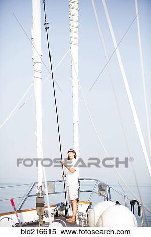 Stock Photography - Caucasian woman standing on sailboat deck. Fotosearch