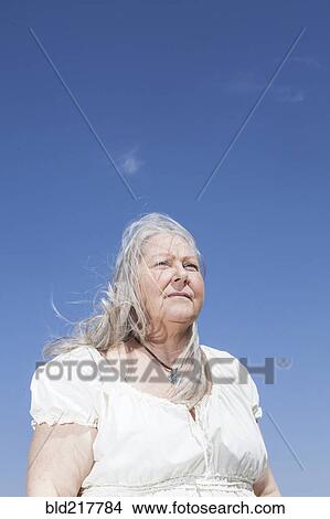 Picture - Caucasian woman standing under blue sky. Fotosearch