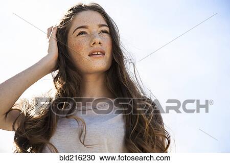 Stock Image - Caucasian woman standing under blue sky. Fotosearch