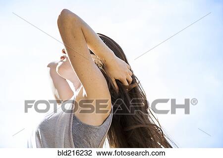Stock Image - Caucasian woman standing under blue sky. Fotosearch